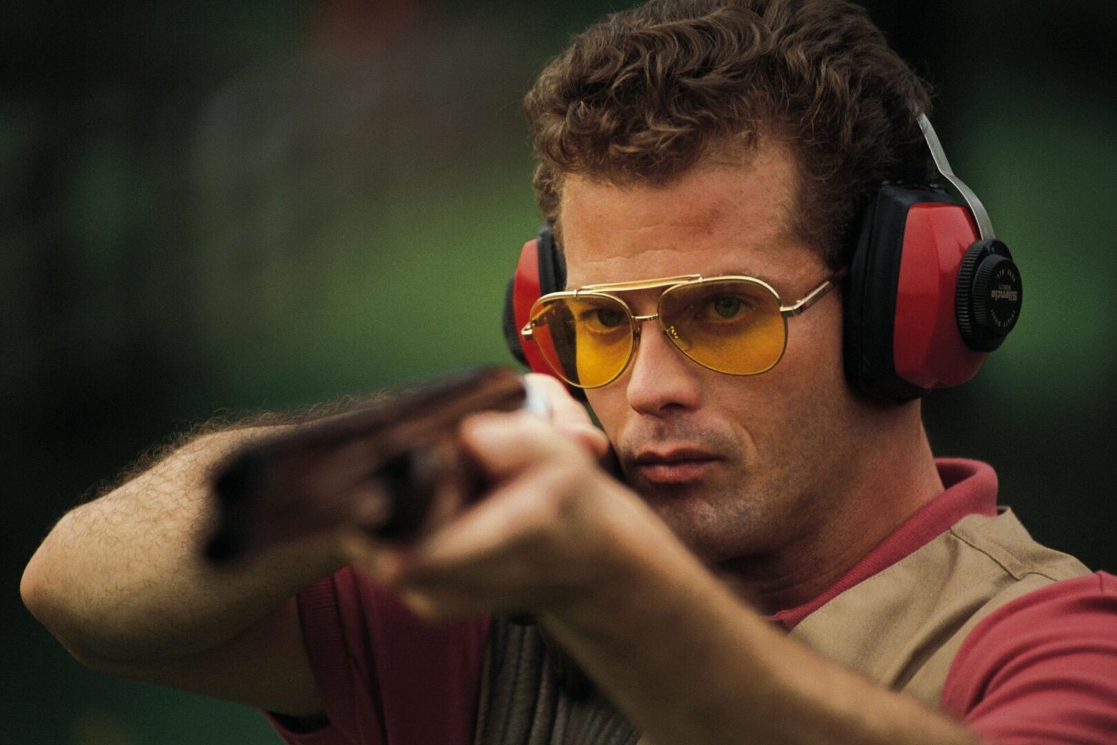 A man wearing ear muffs and holding a gun.