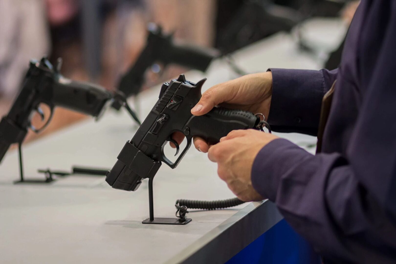 A person holding a gun in front of other guns.