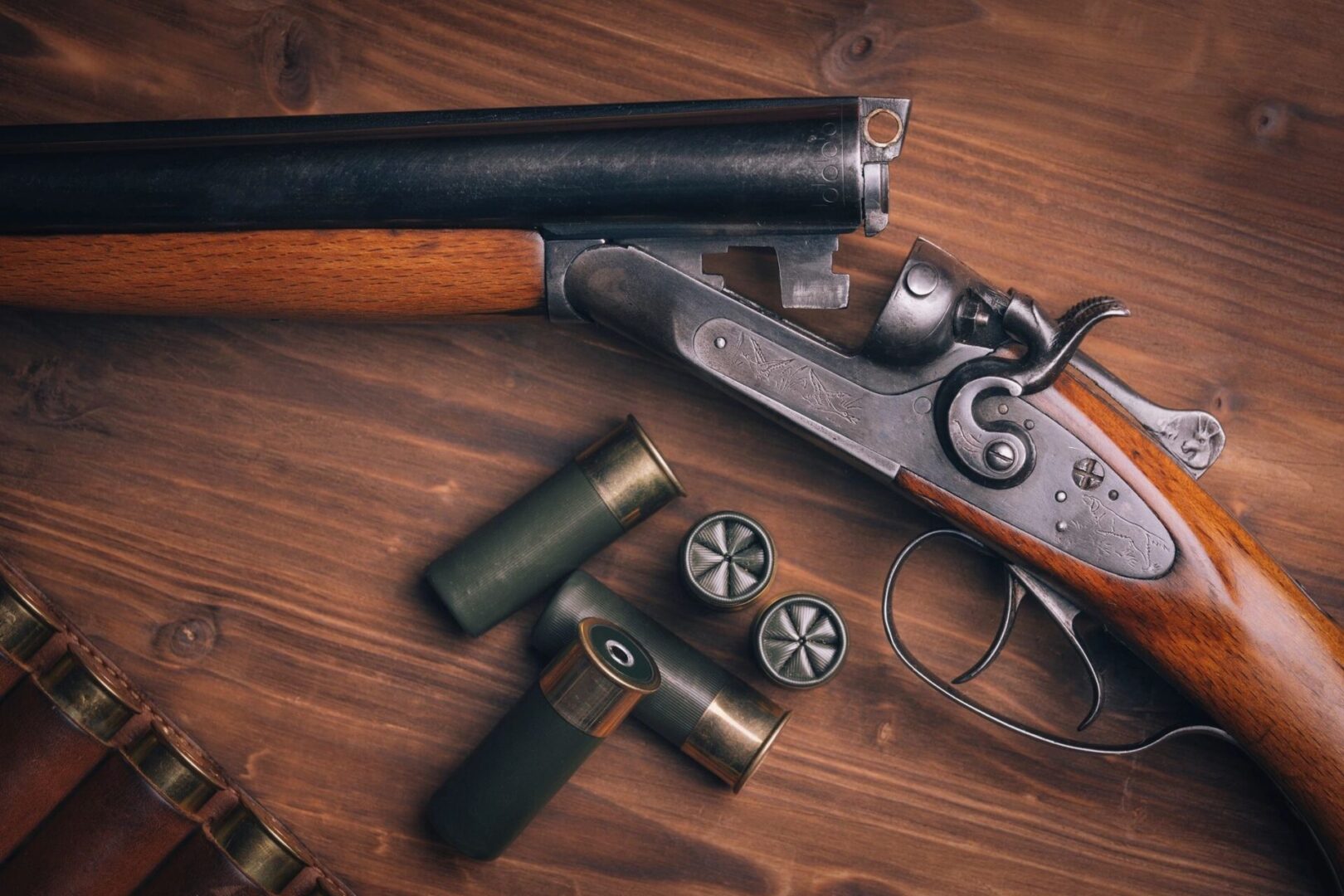 A gun and two shells on top of a table.